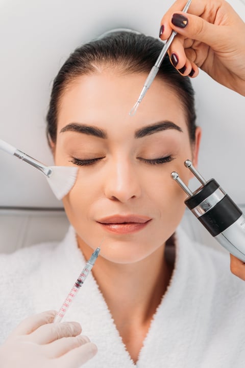 overhead view of woman with various facial treatment equipment around in spa center