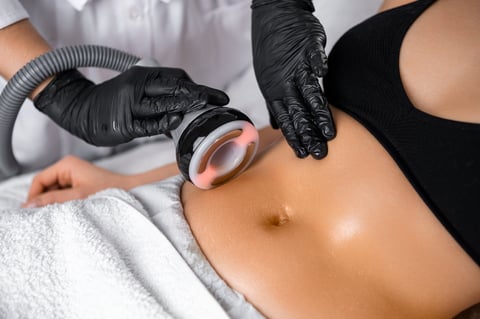 Cosmetologist using ultrasound device while performing lifting procedure on woman belly
