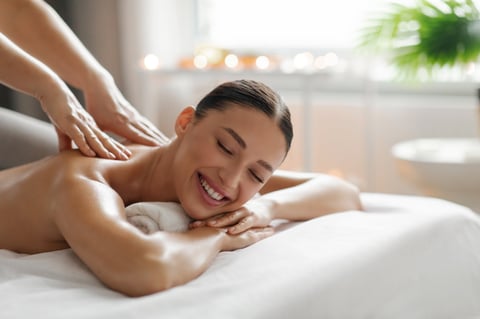 Happy young lady enjoying back massage in luxury beauty salon, wellness day at beauty center