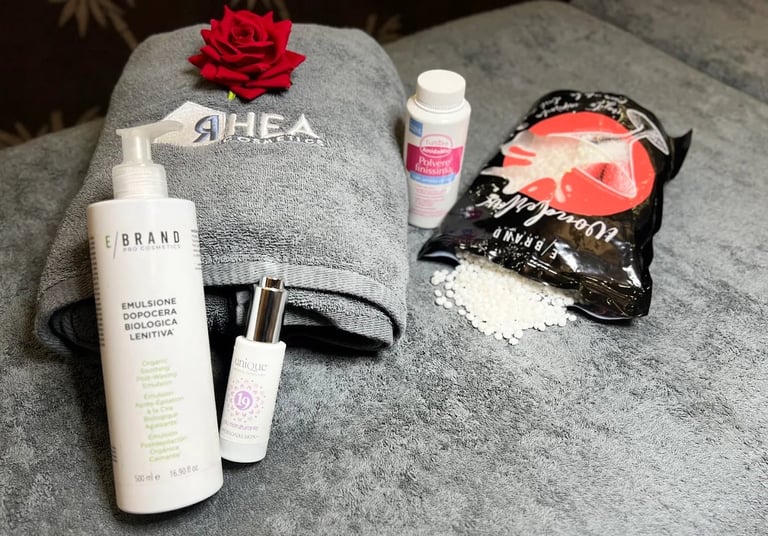 Flatlay of beauty and skincare products including cleansers, serums, and face masks arranged on a gray towel with a red rose