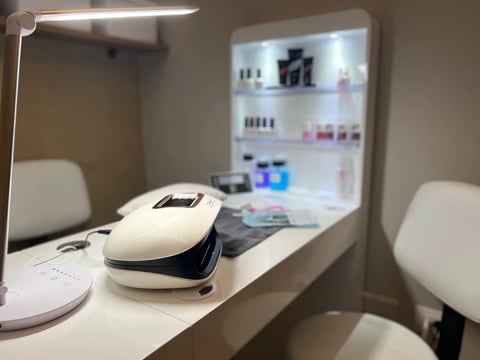 Professional skincare salon vanity with treatment device, makeup products, and illuminated mirror